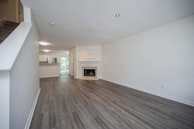 482 Flintlock Ct, Nashville, TN 37217 - unfurnished living room with dark wood-type flooring, recessed lighting, a fireplace with flush hearth, a textured ceiling, and stairway