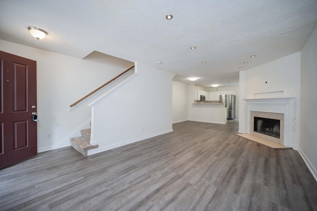 482 Flintlock Ct, Nashville, TN 37217 - unfurnished living room featuring wood finished floors, stairs, a high end fireplace, a textured ceiling, and recessed lighting