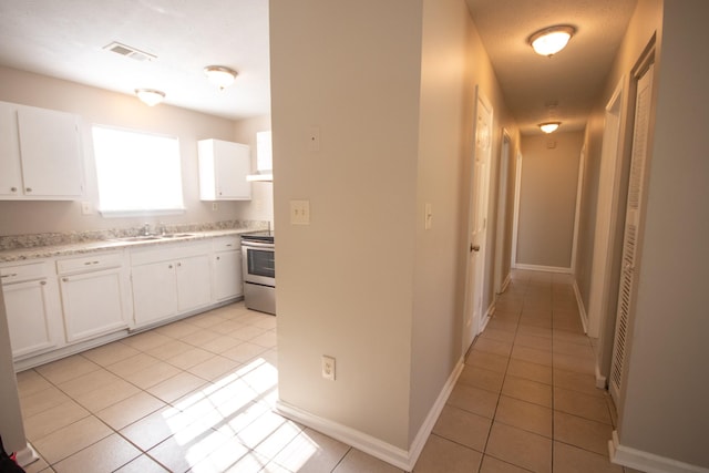 1611 12th Ave N, Nashville, TN 37208 - kitchen featuring electric range, light tile patterned flooring, light countertops, and white cabinetry