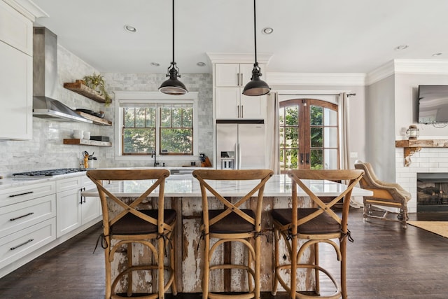 1711 Sevier St, Nashville, TN 37206 - kitchen with stainless steel appliances, wall chimney exhaust hood, plenty of natural light, white cabinetry, and recessed lighting