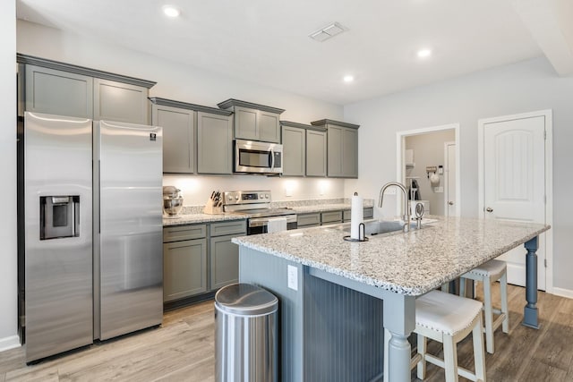 2122 Oak Dr, Murfreesboro, TN 37128 - kitchen with appliances with stainless steel finishes, gray cabinets, light wood-style flooring, a kitchen island with sink, and recessed lighting