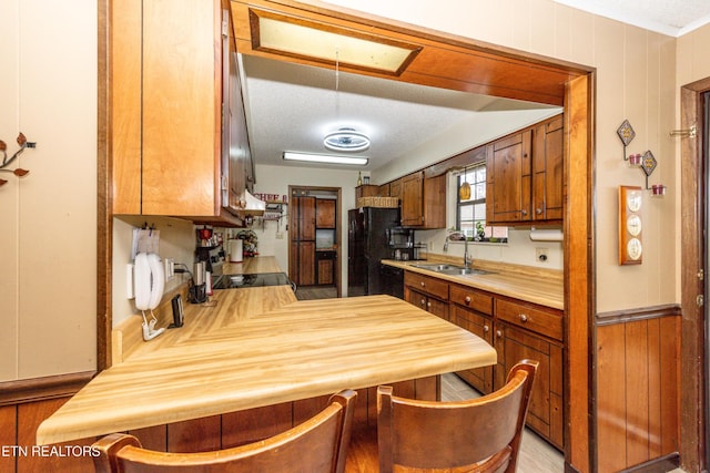311 E Chestnut Hill Rd, Townsend, TN 37882 - kitchen with a peninsula, brown cabinetry, wooden walls, a kitchen breakfast bar, and range with electric stovetop