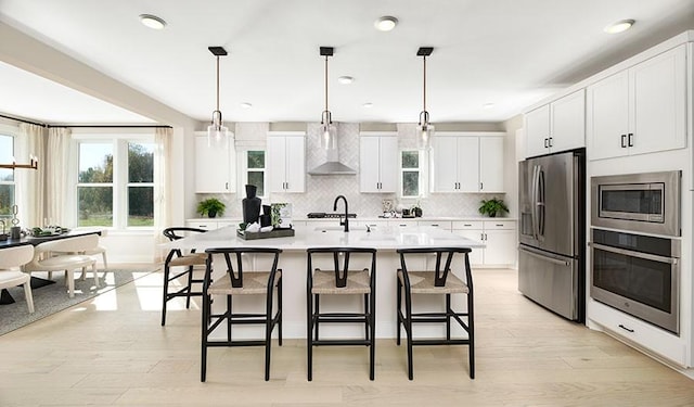 27 Cowan Ct, Mount Juliet, TN 37122 - kitchen featuring appliances with stainless steel finishes, wall chimney exhaust hood, a kitchen breakfast bar, light countertops, and tasteful backsplash
