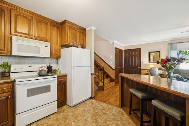 7180 Elrod Rd, Fairview, TN 37062 - kitchen featuring white appliances, a breakfast bar area, brown cabinetry, and wainscoting