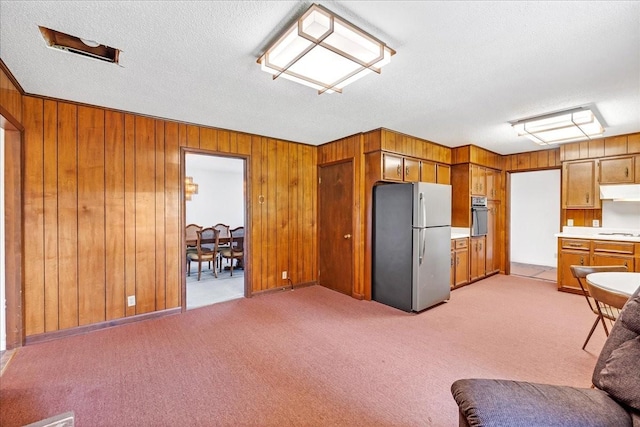 89 Belmar Cir, Manchester, TN 37355 - kitchen with freestanding refrigerator, oven, brown cabinets, light countertops, and wooden walls