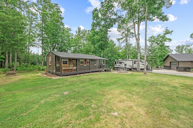 634 Cowboy Way, Jamestown, TN 38556 - view of grassy yard featuring an outdoor structure, gravel driveway, a garage, view of wooded area, and a wooden deck