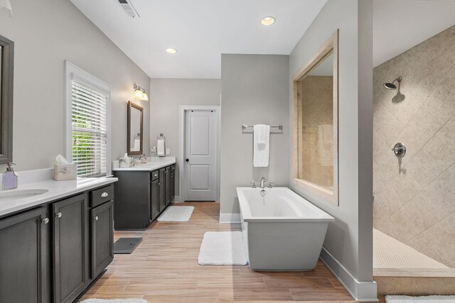 730 Fontwell Ln, Franklin, TN 37064 - bathroom featuring two vanities, a freestanding bath, tiled shower, wood finished floors, and recessed lighting