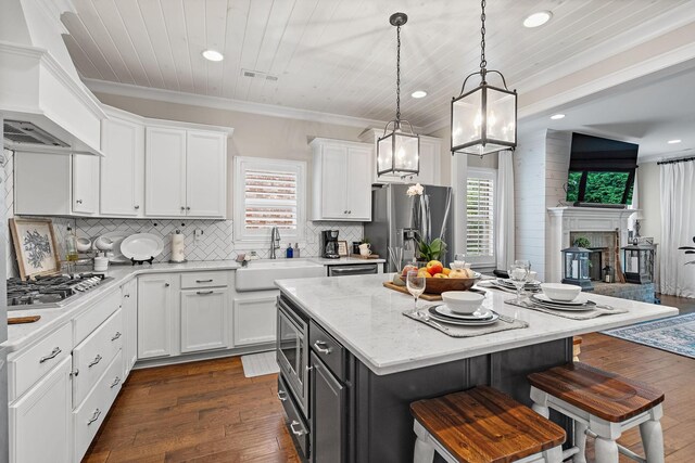 730 Fontwell Ln, Franklin, TN 37064 - kitchen with stainless steel appliances, custom range hood, a kitchen bar, white cabinets, and ornamental molding