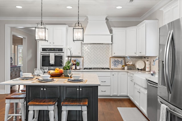 730 Fontwell Ln, Franklin, TN 37064 - kitchen with stainless steel appliances, custom range hood, dark wood-type flooring, white cabinetry, and ornamental molding