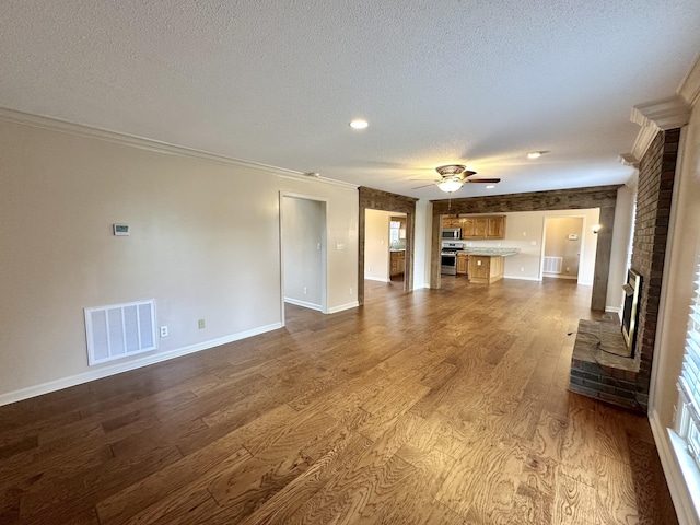 1759 Ardmore Hwy, Taft, TN 38488 - unfurnished living room with a textured ceiling, ornamental molding, dark wood-style floors, a ceiling fan, and a fireplace