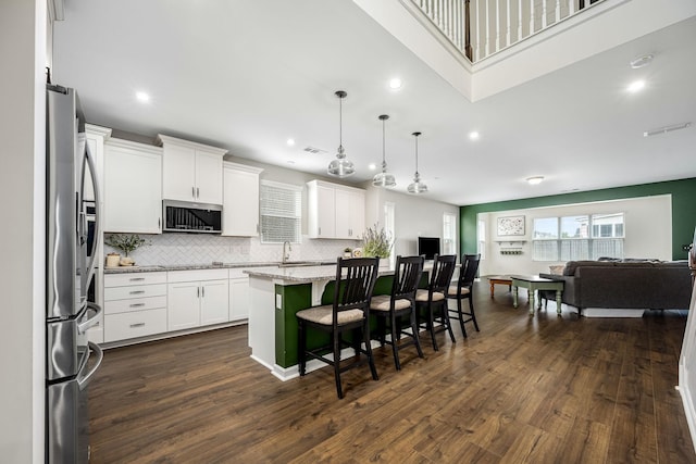 810 Corlew St, Murfreesboro, TN 37130 - kitchen with appliances with stainless steel finishes, open floor plan, decorative backsplash, a kitchen island, and white cabinetry