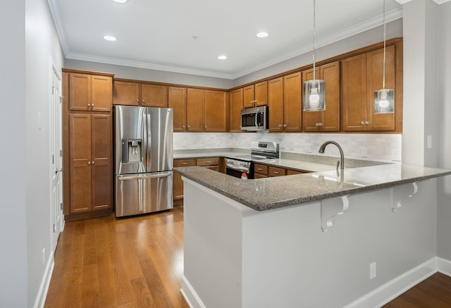 307 Seven Springs Way Unit 103, Brentwood, TN 37027 - kitchen featuring appliances with stainless steel finishes, brown cabinets, a peninsula, light stone countertops, and crown molding