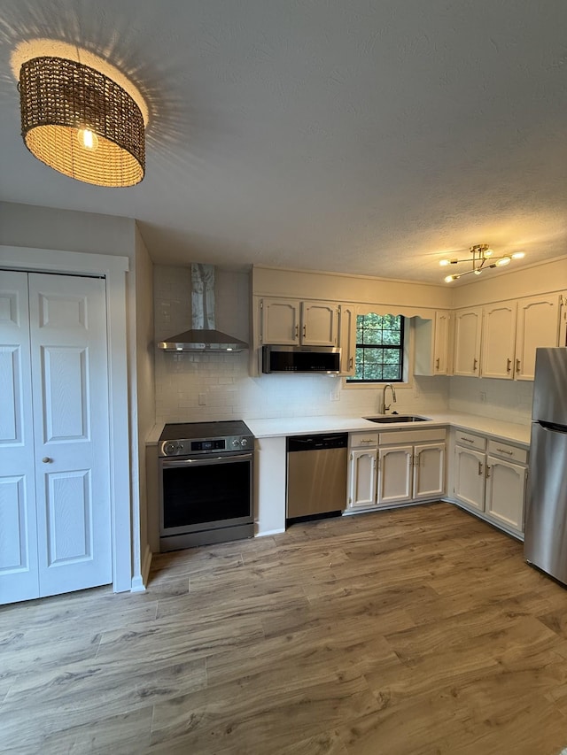 1012 Hollis Ln, White House, TN 37188 - kitchen featuring wall chimney range hood, stainless steel appliances, light countertops, wood finished floors, and backsplash