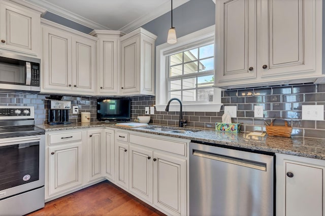 4313 Glasgow Rd, Spring Hill, TN 37174 - kitchen with appliances with stainless steel finishes, ornamental molding, tasteful backsplash, dark stone countertops, and wood finished floors