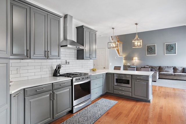 2507 Patricia Cir, Murfreesboro, TN 37128 - kitchen with stainless steel range with gas stovetop, wall chimney exhaust hood, gray cabinetry, open floor plan, and a peninsula