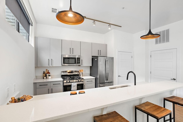 1002 Division St Unit 403, Nashville, TN 37203 - kitchen with appliances with stainless steel finishes, gray cabinets, a kitchen breakfast bar, and hanging light fixtures