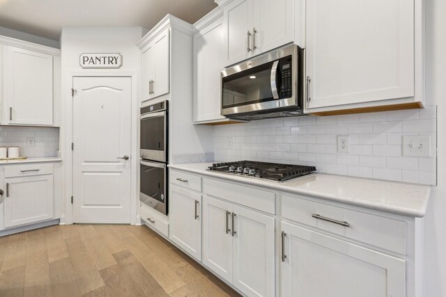 6807 Kew Gdn, Smyrna, TN 37167 - kitchen featuring stainless steel appliances, light countertops, light wood-style flooring, backsplash, and white cabinets