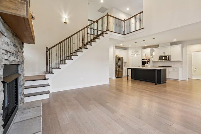 6807 Kew Gdn, Smyrna, TN 37167 - unfurnished living room featuring a high ceiling, a stone fireplace, stairway, light wood-style flooring, and recessed lighting