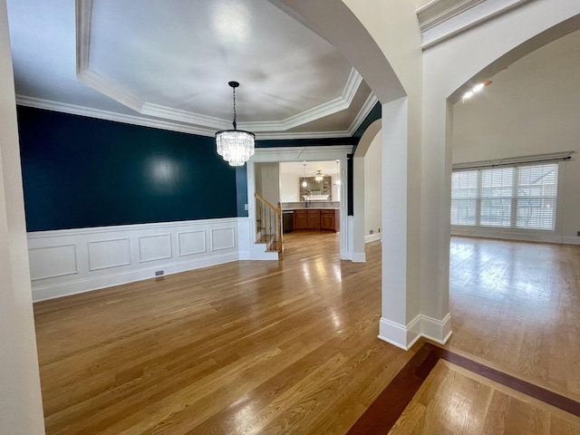 3325 Geneva Dr, Murfreesboro, TN 37128 - unfurnished dining area with arched walkways, light wood-style flooring, a tray ceiling, ornamental molding, and a chandelier