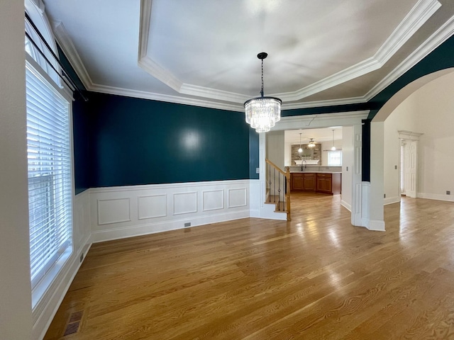 3325 Geneva Dr, Murfreesboro, TN 37128 - unfurnished dining area featuring arched walkways, a chandelier, light wood finished floors, ornamental molding, and a tray ceiling