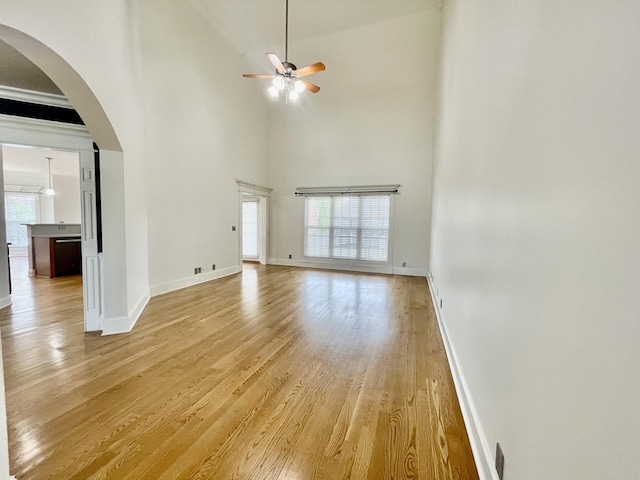 3325 Geneva Dr, Murfreesboro, TN 37128 - unfurnished living room featuring light wood-style floors, a ceiling fan, arched walkways, and a high ceiling