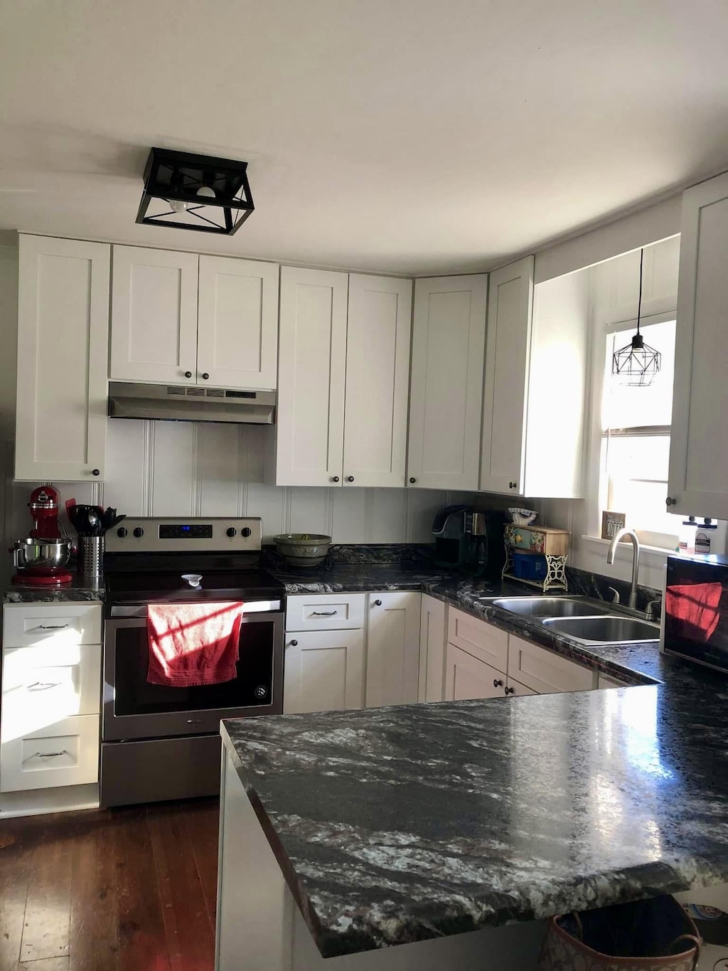 1109 N Charlotte St, Dickson, TN 37055 - kitchen with stainless steel electric stove, under cabinet range hood, dark wood-style flooring, a peninsula, and dark stone countertops