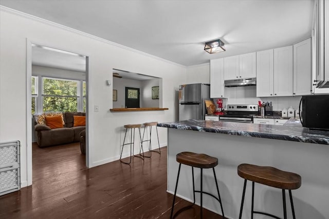 1109 N Charlotte St, Dickson, TN 37055 - kitchen featuring stainless steel appliances, under cabinet range hood, a peninsula, dark wood finished floors, and white cabinetry