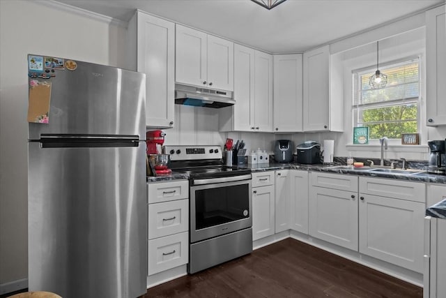 1109 N Charlotte St, Dickson, TN 37055 - kitchen with stainless steel appliances, under cabinet range hood, dark countertops, dark wood-style floors, and white cabinetry