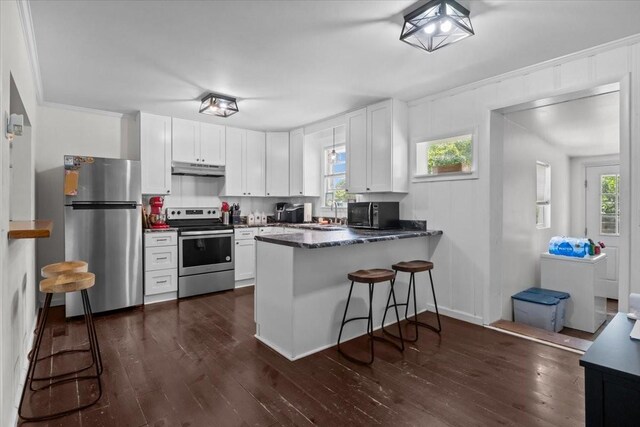 1109 N Charlotte St, Dickson, TN 37055 - kitchen with stainless steel appliances, a peninsula, dark wood-type flooring, white cabinetry, and a kitchen breakfast bar