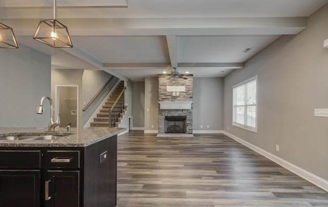 203 Eagles Talon Ct, Clarksville, TN 37040 - kitchen featuring a fireplace, beamed ceiling, wood finished floors, light stone counters, and decorative light fixtures