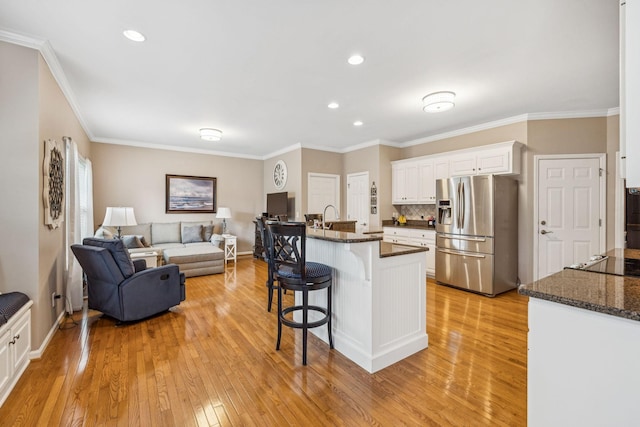 1011 Brixworth Dr, Thompsons Station, TN 37179 - kitchen with stainless steel fridge with ice dispenser, a kitchen breakfast bar, light wood finished floors, white cabinetry, and ornamental molding