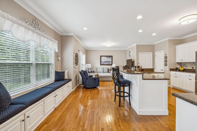 1011 Brixworth Dr, Thompsons Station, TN 37179 - kitchen with white cabinets, light wood finished floors, crown molding, a kitchen breakfast bar, and open floor plan
