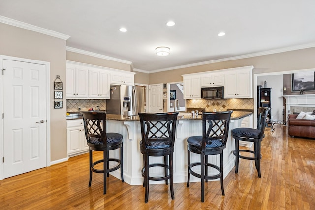 1011 Brixworth Dr, Thompsons Station, TN 37179 - kitchen with black microwave, stainless steel fridge with ice dispenser, backsplash, light wood-type flooring, and crown molding