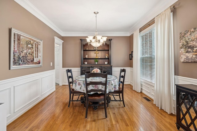 1011 Brixworth Dr, Thompsons Station, TN 37179 - dining space featuring a chandelier, light wood finished floors, a decorative wall, a wainscoted wall, and crown molding