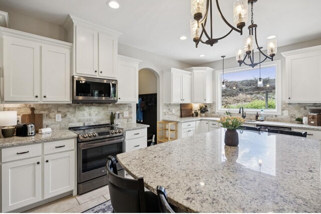 718 Excalibur Ct, Smyrna, TN 37167 - kitchen featuring appliances with stainless steel finishes, white cabinetry, arched walkways, backsplash, and pendant lighting