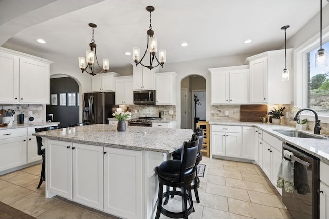 718 Excalibur Ct, Smyrna, TN 37167 - kitchen featuring stainless steel appliances, arched walkways, decorative backsplash, a center island, and recessed lighting