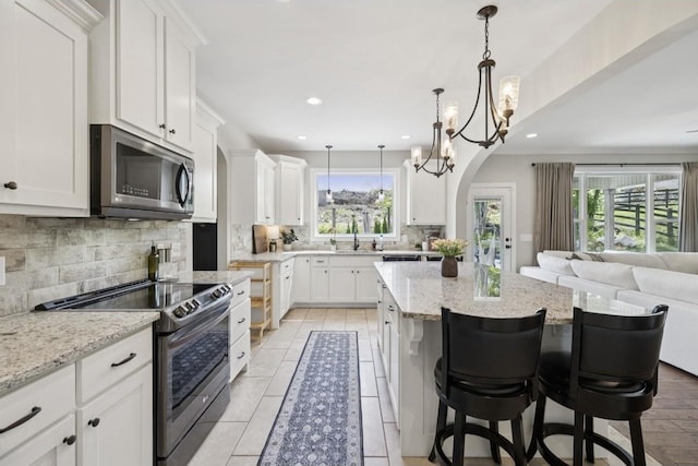 718 Excalibur Ct, Smyrna, TN 37167 - kitchen with range with electric stovetop, stainless steel microwave, decorative backsplash, open floor plan, and a kitchen island