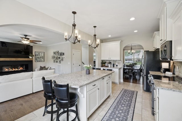 718 Excalibur Ct, Smyrna, TN 37167 - kitchen featuring range with electric cooktop, stainless steel microwave, arched walkways, a chandelier, and tasteful backsplash