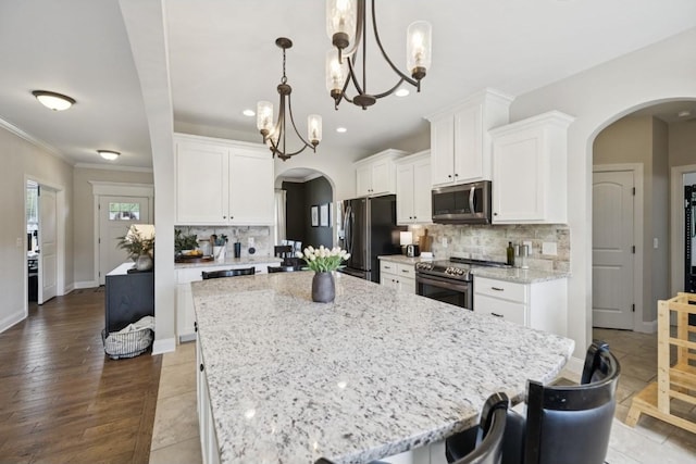 718 Excalibur Ct, Smyrna, TN 37167 - kitchen featuring appliances with stainless steel finishes, arched walkways, backsplash, white cabinetry, and recessed lighting