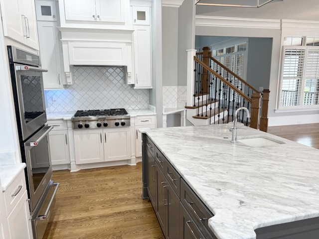 1430 Avellino Cir, Murfreesboro, TN 37130 - kitchen with appliances with stainless steel finishes, white cabinets, light wood-type flooring, decorative backsplash, and ornamental molding