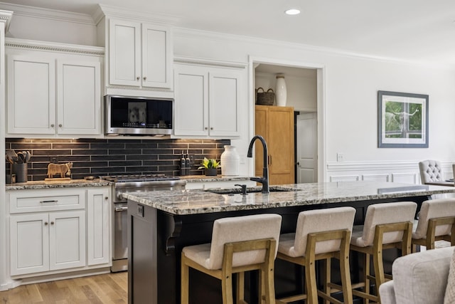 967 Nashs Nook, Columbia, TN 38401 - kitchen with stainless steel appliances, ornamental molding, light stone counters, a breakfast bar area, and light wood-style flooring