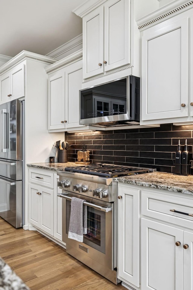967 Nashs Nook, Columbia, TN 38401 - kitchen featuring appliances with stainless steel finishes, tasteful backsplash, light wood finished floors, white cabinetry, and light stone counters