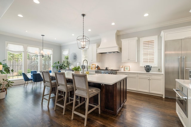 1014B Noelton Ave, Nashville, TN 37204 - kitchen featuring custom range hood, light countertops, a center island with sink, a chandelier, and backsplash