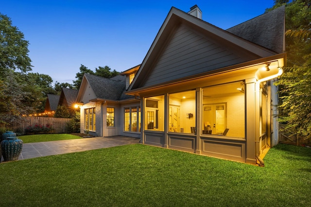 1014B Noelton Ave, Nashville, TN 37204 - back of house at dusk featuring a sunroom, a patio, a chimney, and roof with shingles
