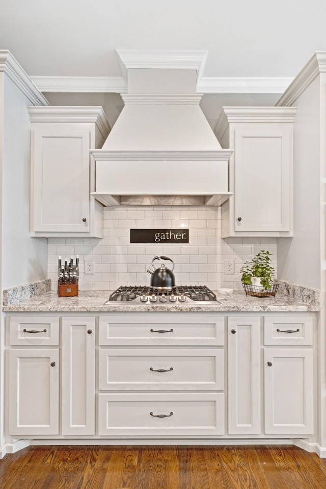 2003 Imagine Cir, Spring Hill, TN 37174 - kitchen featuring stainless steel gas cooktop, wall chimney range hood, white cabinets, ornamental molding, and tasteful backsplash