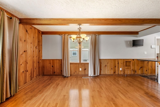 3509 Lafayette Rd, Hopkinsville, KY 42240 - unfurnished dining area featuring a textured ceiling, a chandelier, beamed ceiling, light wood-style flooring, and wooden walls