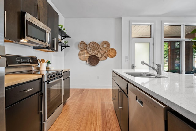 201 S 11th St, Nashville, TN 37206 - kitchen with stainless steel appliances, light wood-style floors, dark brown cabinetry, light stone counters, and open shelves
