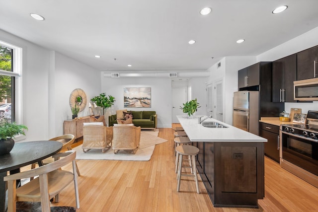 201 S 11th St, Nashville, TN 37206 - kitchen with appliances with stainless steel finishes, a breakfast bar, light countertops, light wood-style floors, and a kitchen island with sink