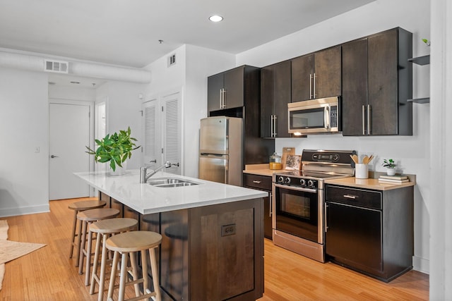 201 S 11th St, Nashville, TN 37206 - kitchen featuring appliances with stainless steel finishes, a breakfast bar, light countertops, light wood-style floors, and recessed lighting