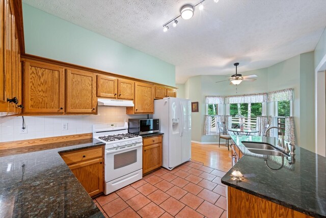 191 Spicer Rd, Burns, TN 37029 - kitchen with white appliances, under cabinet range hood, tasteful backsplash, light tile patterned floors, and brown cabinets